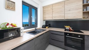 A modern kitchen with a built-in oven, a microwave, and a sink. - Apartment Skyline (Konavle)