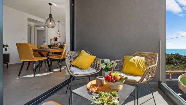 A modern balcony with wicker chairs, a glass table, and a bowl of fruit. - Apartment Skyline (Konavle)