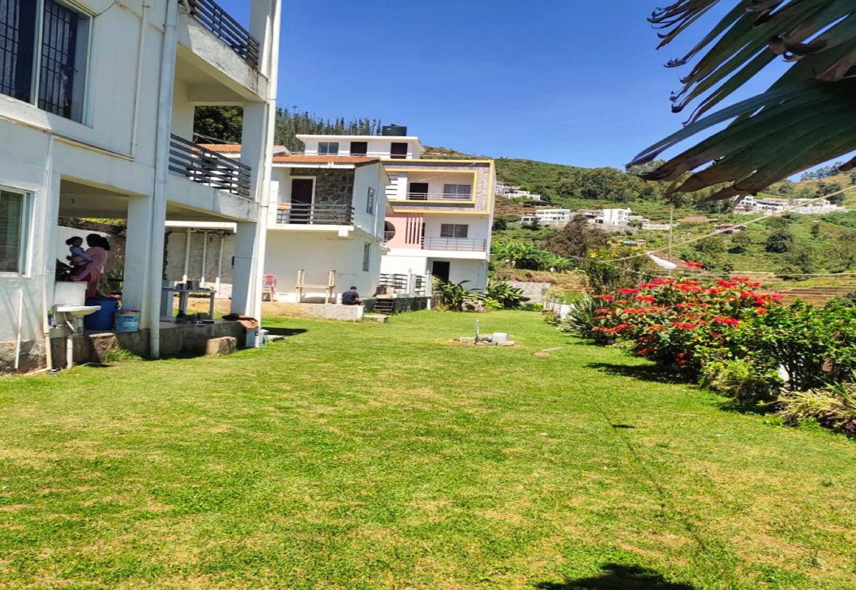 Un edificio residencial de varios pisos con jardín césped y una pequeña zona de patio.