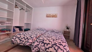 A bedroom with two beds, a wardrobe, a ceiling fan, a wall-mounted decoration, and a potted plant. - Casa Teide, ground floor Parque Santiago 1, heated pool, 100 m to sea+beach (Playa de la Américas)