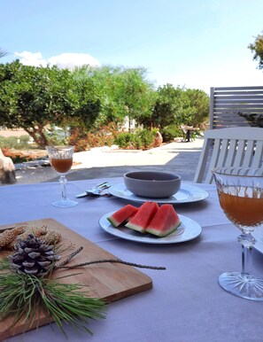 An outdoor dining table with plates of watermelon, a bowl, and glasses of a beverage. - Koukounari Cottage Paros, Apartment With sea View (Paros)