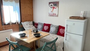 A cozy dining area with a wooden table, green chairs, a white refrigerator, and a wall with a poster.