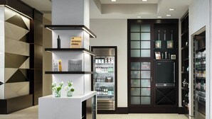 A modern hotel lobby with a reception desk, a refrigerator stocked with beverages, and a display of books and bottles. - AC Hotel by Marriott Jackson Ridgeland (Ridgeland)