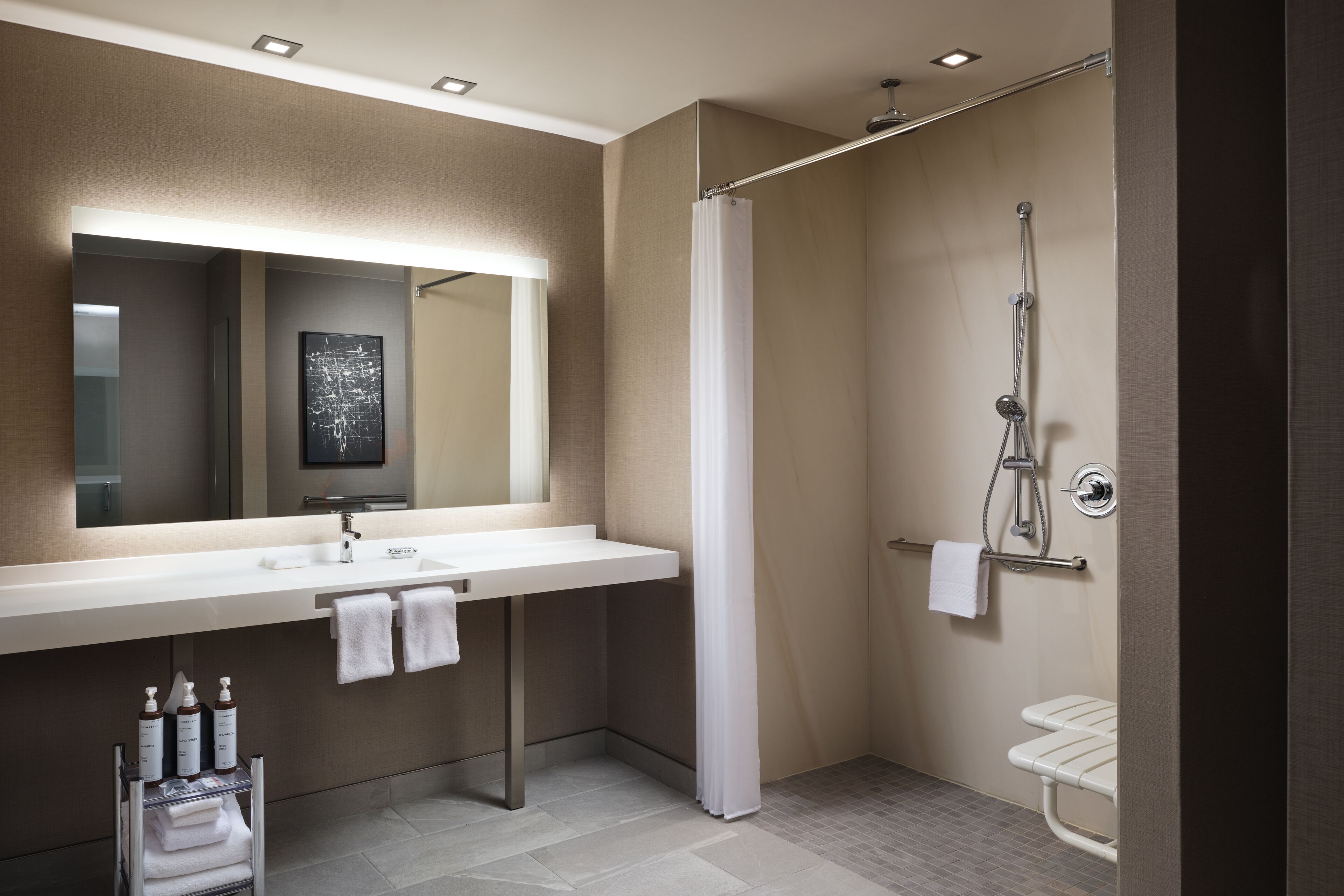 A modern bathroom with a large mirror, a shower, and a sink.