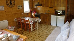Una cucina accogliente con mobili in legno, un tavolo da pranzo con sedie, una sveglia e un forno a microonde.