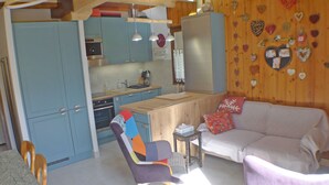 A cozy kitchen with blue cabinets, a wooden dining table, and a purple chair.