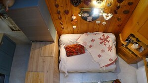 A cozy room with a bed, a small table with a bowl and a plate, and a wooden cabinet.