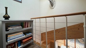 Eine Treppe mit hölzernem Geländer, ein Bücherregal mit Büchern und ein an der Wand befestigter Hirschkopf.