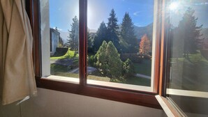 Una stanza con un'ampia finestra, rivestimenti in legno e vista su un paesaggio verde con alberi e un edificio.
