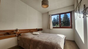 Una camera da letto con un letto in legno, una lampada da comodino, una finestra vista alberi e un lampadario.