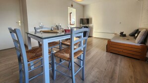 Zona pranzo con tavolo in vetro, sedie blu e pavimento in legno.