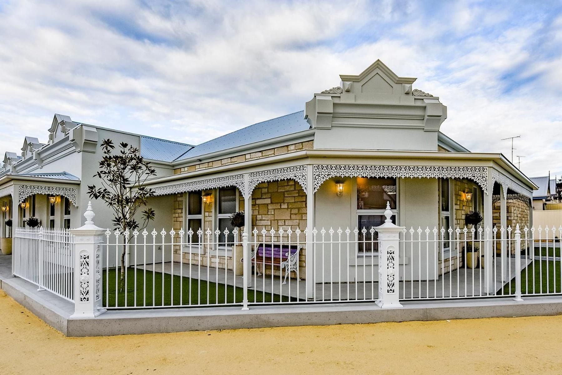 A Victorian-style building with a white picket fence, a covered porch, and a brick facade.