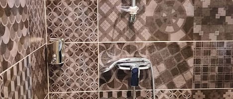 A shower area with a modern design, featuring geometric and floral patterned tiles.