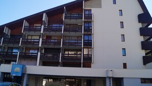 Un edificio de varios pisos con balcones, un cartel que dice 'Hotel Solace' y un coche estacionado frente a él.