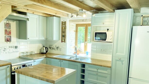 A modern kitchen with light blue cabinets, a wooden countertop, a built-in stove, and a microwave. - The perfect Couple's Retreat (Abjat-sur-Bandiat)