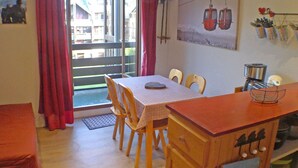 A dining area with a table, chairs, a wooden cabinet, and a view of a balcony with red curtains. - Apartment for 5 with private balcony and parking in Samoëns (Samoëns)