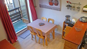 A small dining area with a table and chairs, a kitchen with a coffee maker, and a view of a mountain through a window. - Apartment for 5 with private balcony and parking in Samoëns (Samoëns)