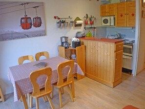 A small kitchen with wooden cabinets, a dining table with chairs, and a kitchen island.