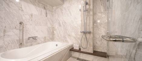 A modern bathroom with a marble shower, a bathtub, and a glass-enclosed shower area.