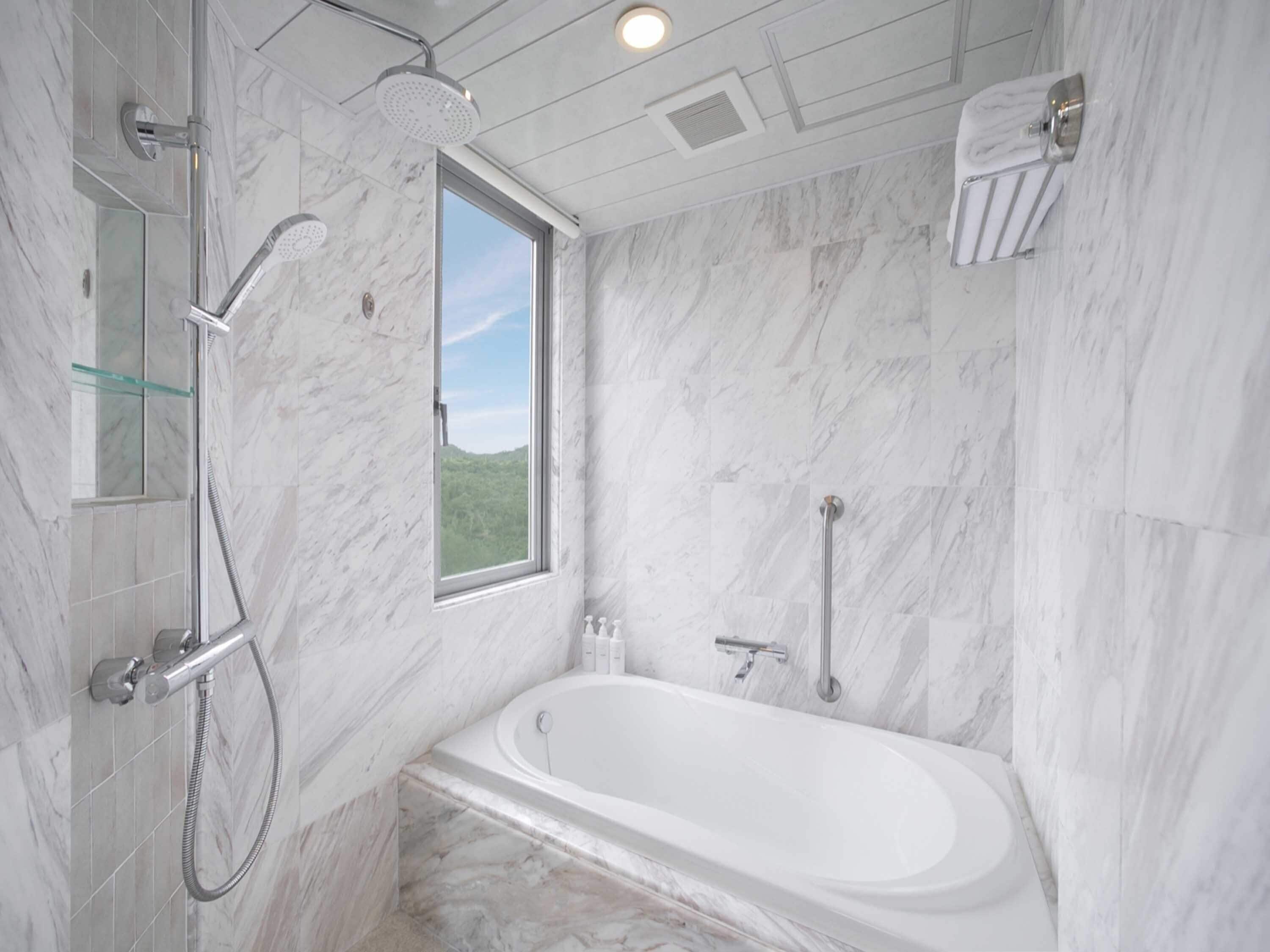 A modern bathroom with a bathtub, a shower, and a window.