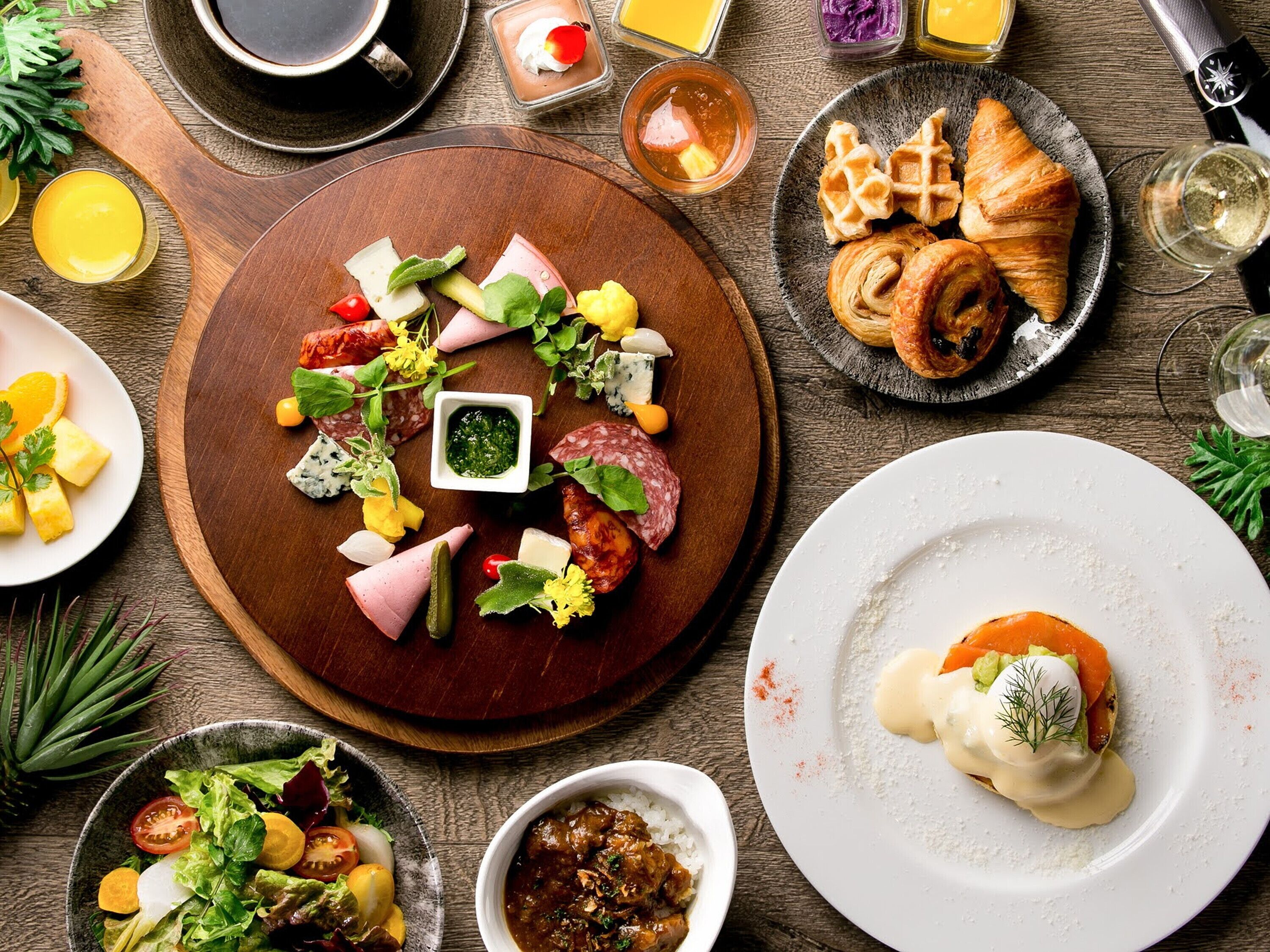 A breakfast setting with various food items, including pastries, meats, and a salad.