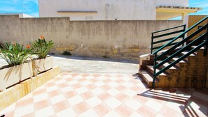 A courtyard with a checkered floor, a staircase, and planters with plants.
