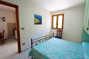 Una camera da letto con un letto, una finestra, una sedia e un quadro appeso al muro.