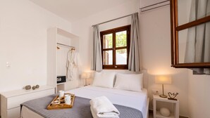 Hotellihuone, jossa on sänky, yöpöytä, yölamppu, ikkuna verhoilla ja vaatekaappi.