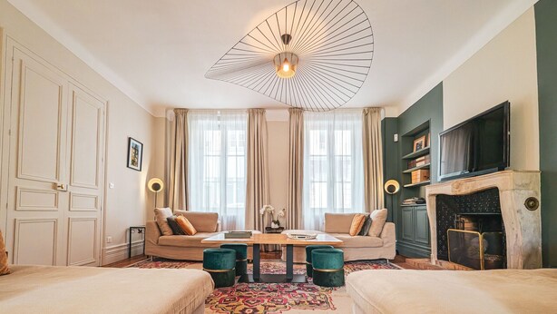 Ein gemütliches Wohnzimmer mit einer Couch, zwei Sesseln, einem Couchtisch, einem Kamin und einem Deckenventilator.
