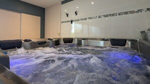 Ein Wellnessbereich mit vier Whirlpools und einer gefliesten Wand mit Mosaikbordüre.