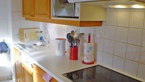 Una cocina con armarios de madera, una encimera blanca, un microondas integrado y una estufa a gas.