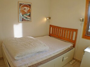 Ein Einzelbett mit Holz-Kopfteil in einem Zimmer mit wei ßen Wänden.