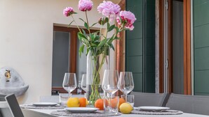A dining table with a vase of flowers, plates, glasses, and oranges. - San Giacomo dall'Orio Garden Apartment R&R (Venecia)