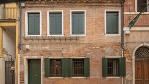 A brick building with three windows and a door, each with green shutters. - San Giacomo dall'Orio Garden Apartment R&R (Venecia)