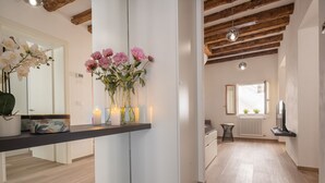 A modern kitchen with a central island, a dining area with a wooden ceiling, and a view of the living room. - San Giacomo dall'Orio Garden Apartment R&R (Venecia)