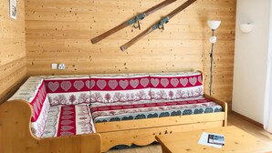 A wooden cabin interior with a sofa, a table, and a lamp. - 6-Person Apartment with Terrace, Parking, and Wi-Fi (Samoëns)
