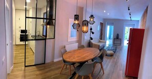 Cozinha moderna com mesa e cadeiras de madeira, geladeira vermelha e luminárias pendentes.