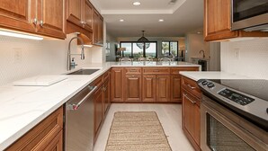 A modern kitchen with wooden cabinets, a stainless steel oven, and a large island with seating.