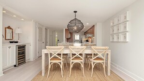 A modern kitchen with a central island, white cabinetry, and a hanging light fixture.