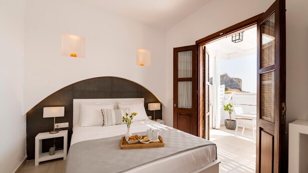 Una camera d'albergo con un letto grande, lampade sui comodini, un vassoio con la colazione e vista sull'esterno.