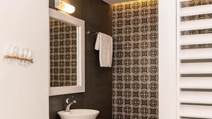 Un bagno con un lavandino bianco, uno specchio e carta da parati decorata.