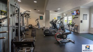 Ein Fitnessstudio mit verschiedenen Trainingsgeräten, darunter Laufbänder, Crosstrainer und Kraftgeräte.