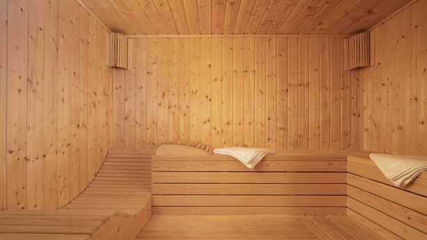 Un sauna avec des bancs en bois et un banc muni d’une serviette.