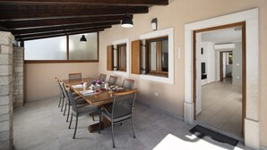 Un espace repas avec une longue table en bois, des chaises et un mur en pierre.