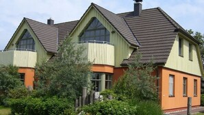 A two-story house with a gabled roof and a balcony on the upper floor.
