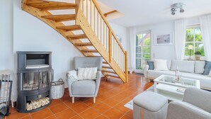 Ein Wohnzimmer mit einer Holztreppe, einem Sofa, einem Glastisch und einem Kamin.