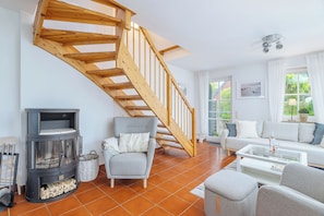 A living room with a wooden staircase, a sofa, a glass coffee table, and a fireplace.