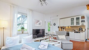 Ein modernes Hotelzimmer mit Bett, Fernseher, Essbereich und Küchenzeile.