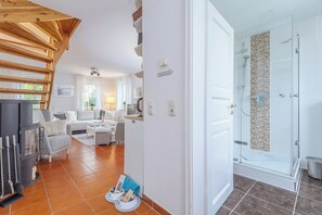 Et moderne interiør med pejs, sofaarrangement, spiseområde og brusebadeværelse.