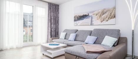 Uma sala de estar moderna com um sofá seccional, uma mesa de centro e uma janela grande com cortinas.